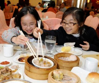 Beracah Lam (right) and Jodi Ho (left) celebrate winning top honors in the 25th Annual Ezra Jack Keats Bookmaking Competition at the restaurant in Brooklyn's Chinatown that inspired their book-Let's Go For Dim Sum. Beracah and Jodi, third graders at P.S. 229, were among the four city-wide winners recognized by the Ezra Jack Keats Foundation in partnership with the NYC Department of Education. The competition was named after the late beloved children's picture book author and illustrator Ezra Jack Keats.  (PRNewsFoto/Ezra Jack Keats Foundation)